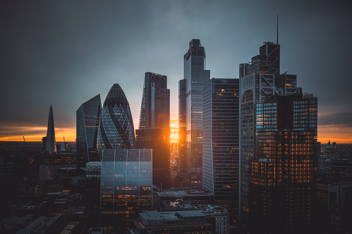 Aerial panoramic view of cityscape skyline with metropole financial district modern skyscrapers during sunrise with illuminated buildings and cloudy sky in London, UK.