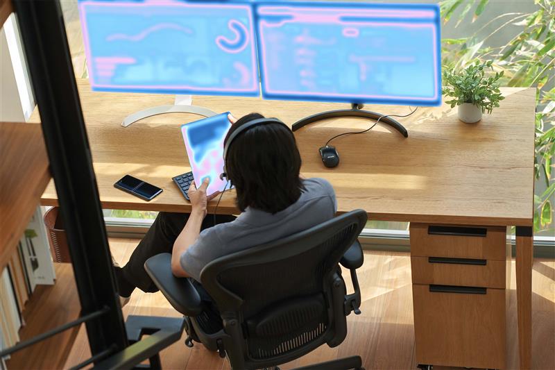 A person sitting at a desk with a computer and tablet