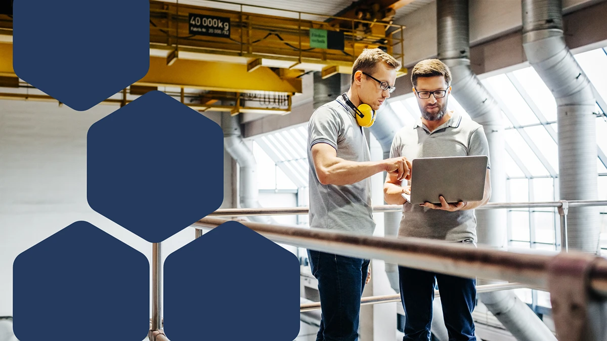 Photo of two engineers in a factory looking at laptop