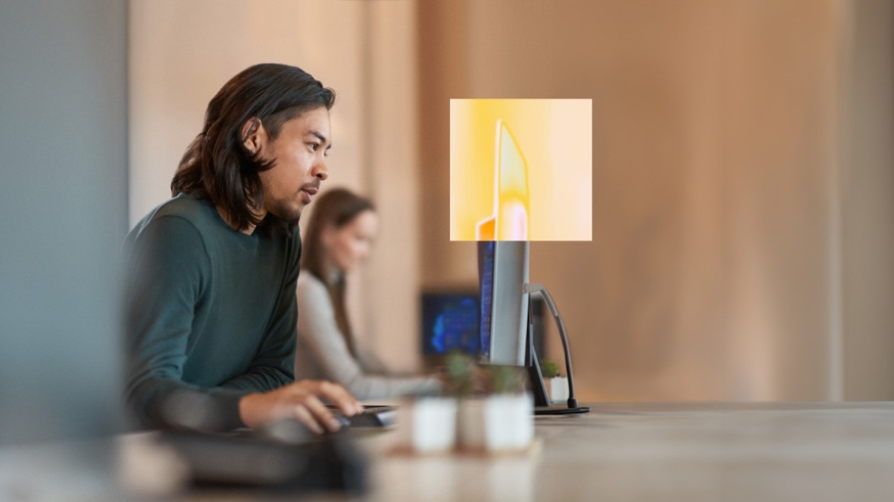 Two people sit at their computers in a work environment.