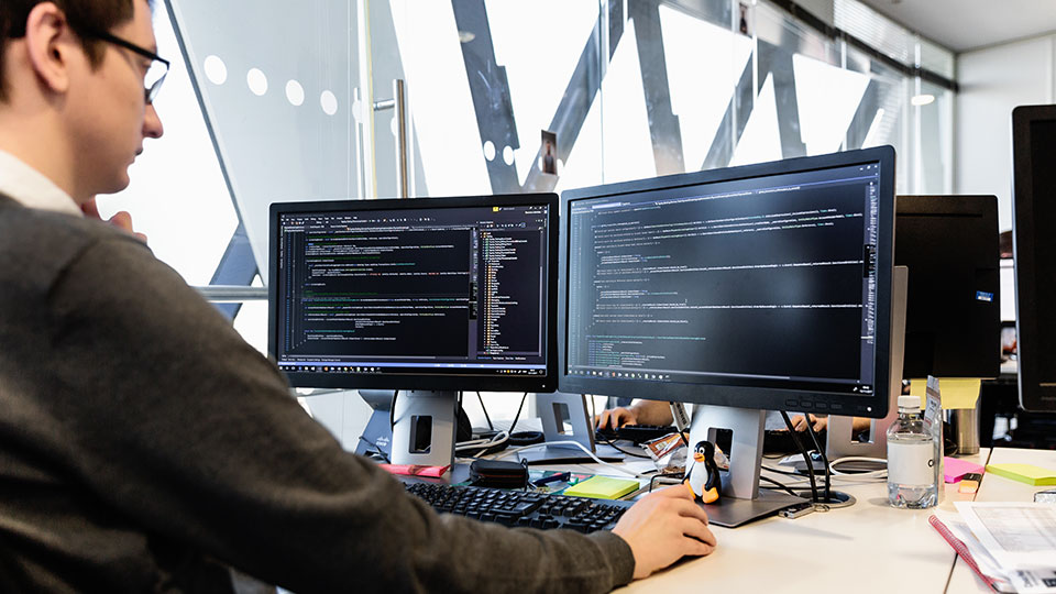 A man works at a desk with dual monitors