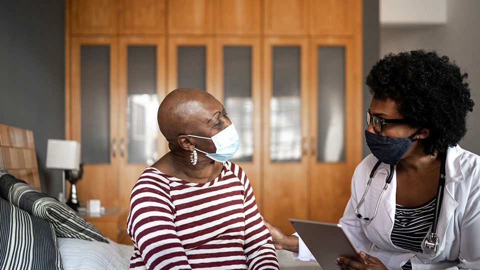 A woman and a medical professional in face masks have a discussion