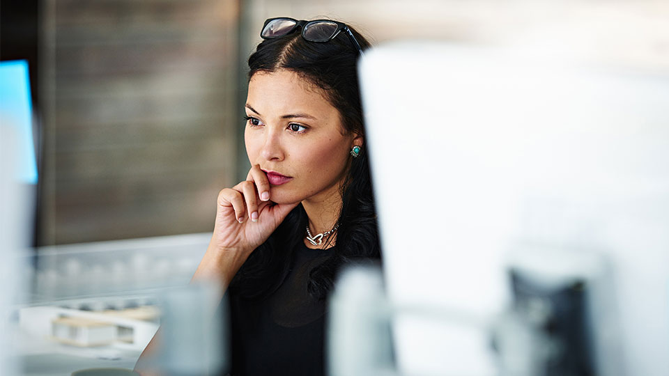 A woman thoughtfully reads a computer display