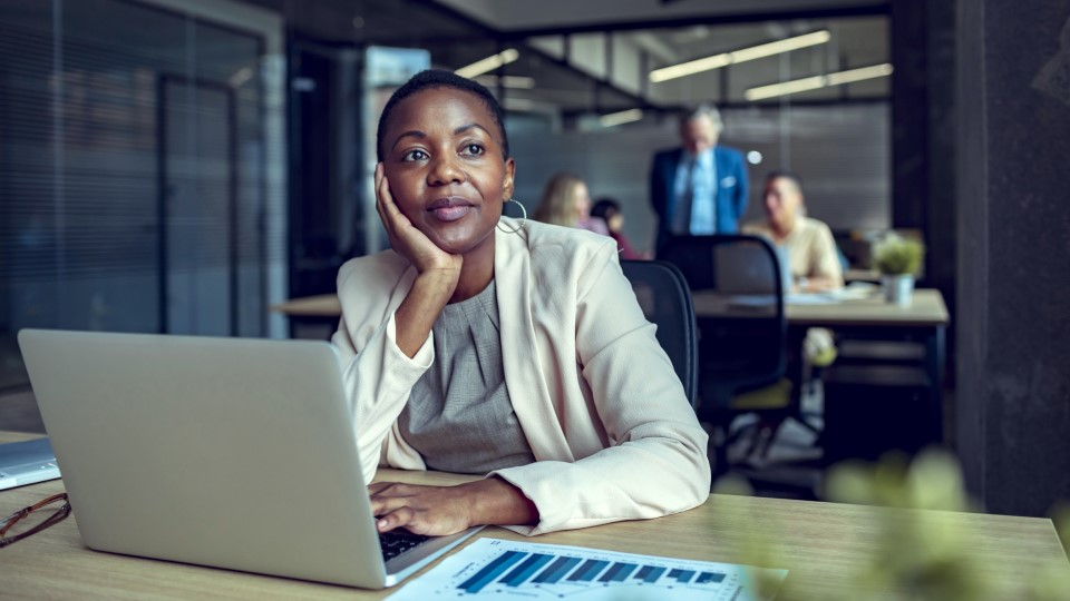 Woman working at computer, looking away thoughtfully