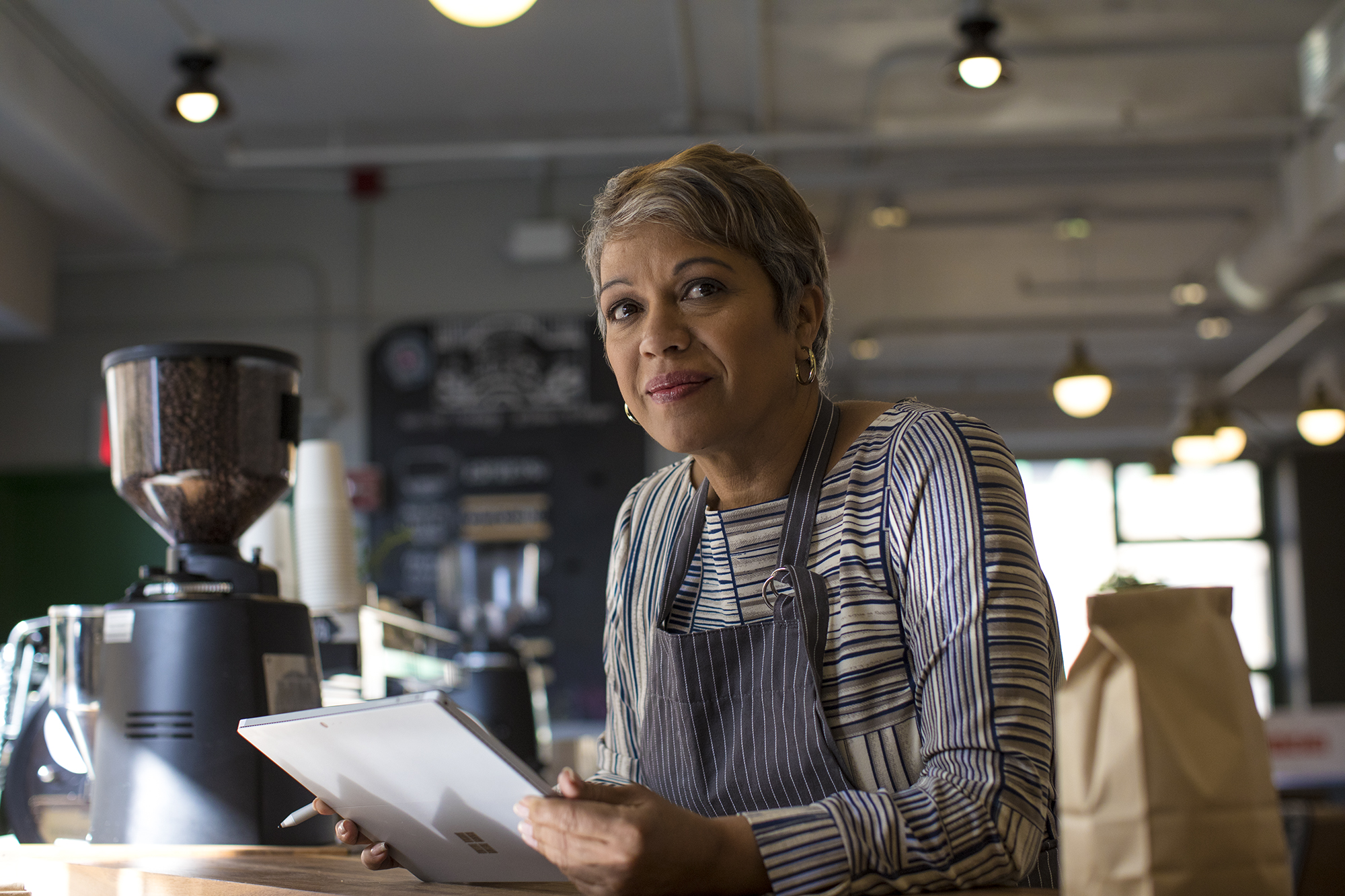 Featured image for Microsoft for Startups blog post titled "Helping small businesses grow with conversational AI assistants" of a frontline worker achieving in retail workspace using Surface.