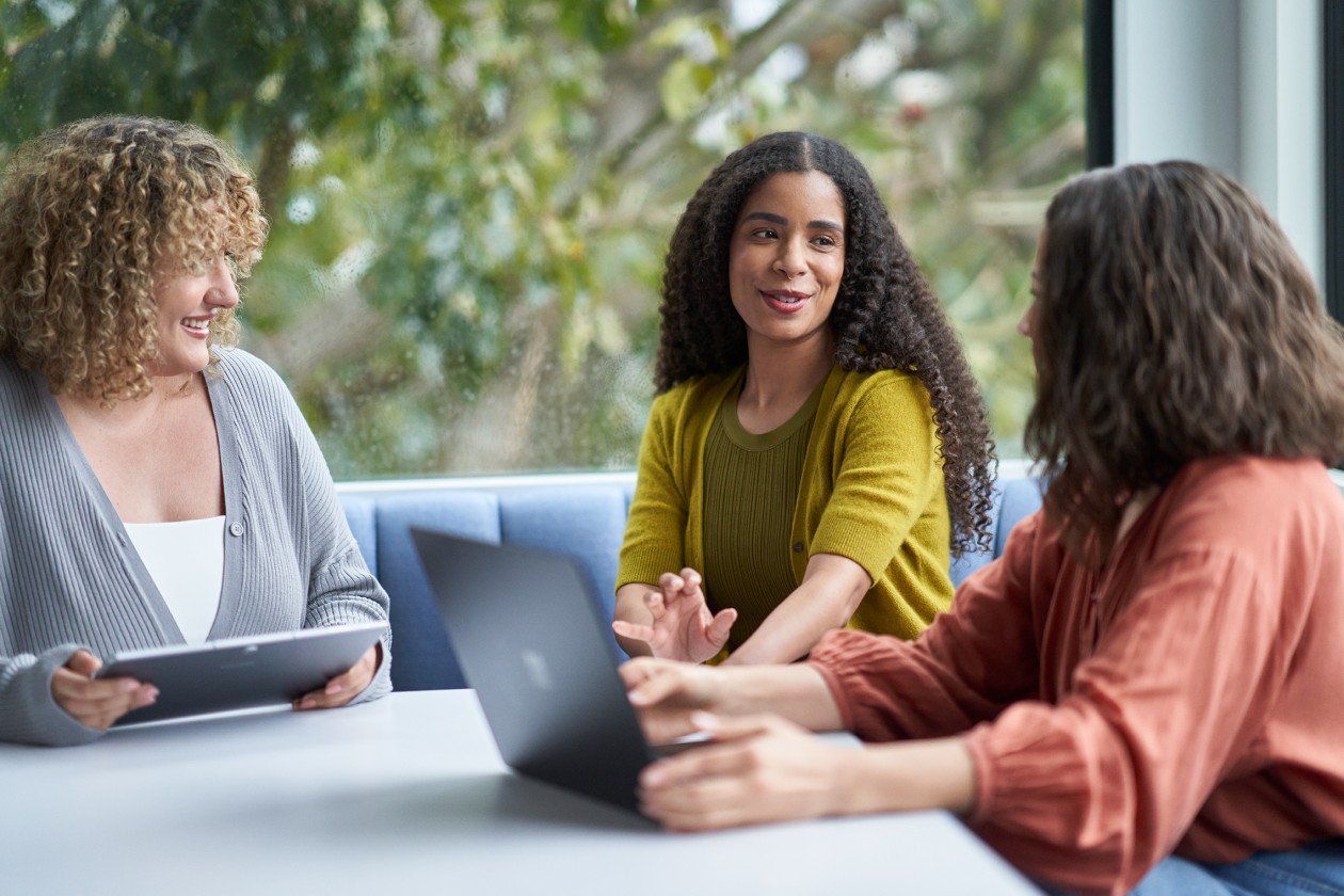 Three women sitting at a desk with a laptop