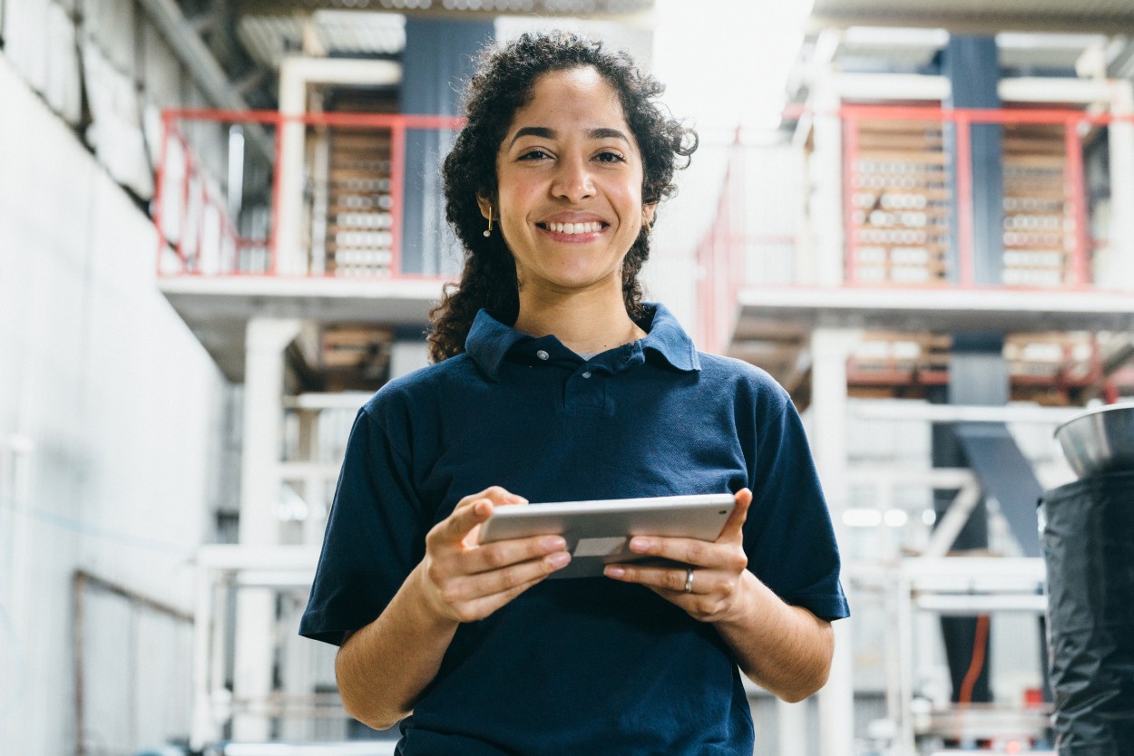 Woman, holding a tablet, working and smiling in a warehouse.
