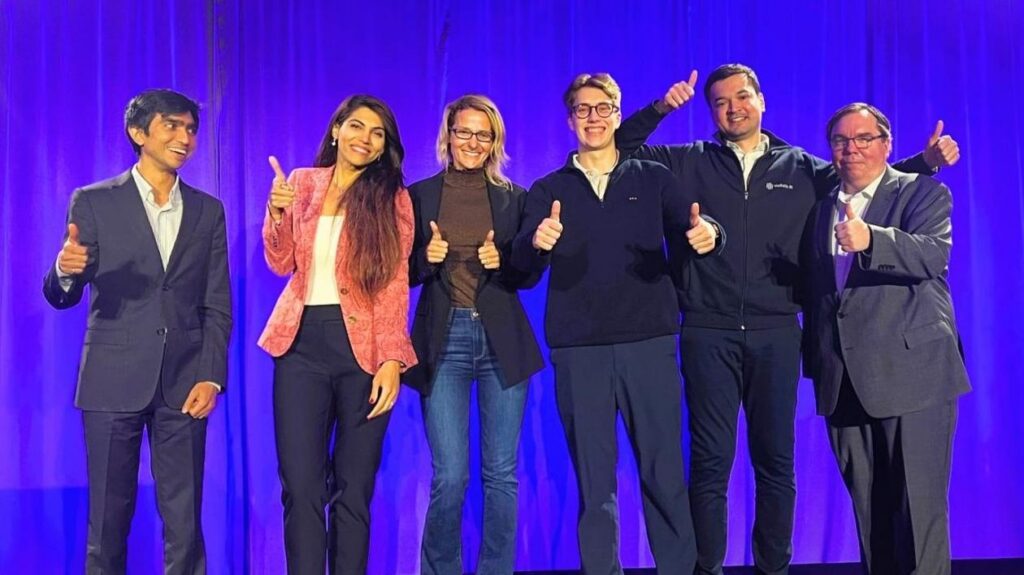 group of people smiling in front of purple backdrop