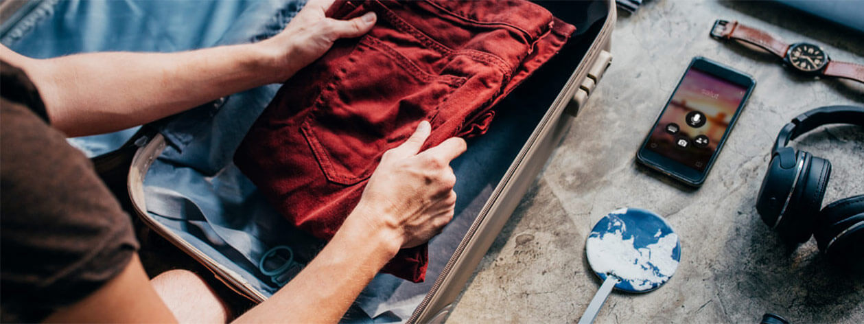 Ένα άτομο συσκευάζει μια βαλίτσα, ενώ ένα έξυπνο τηλέφωνο που εκτελεί την εφαρμογή Microsoft μεταφράστρια βρίσκεται κοντά