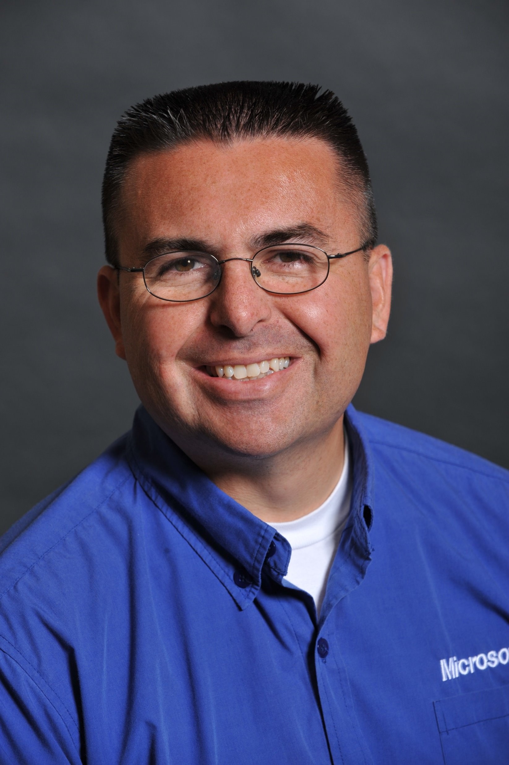 a man wearing glasses and smiling at the camera