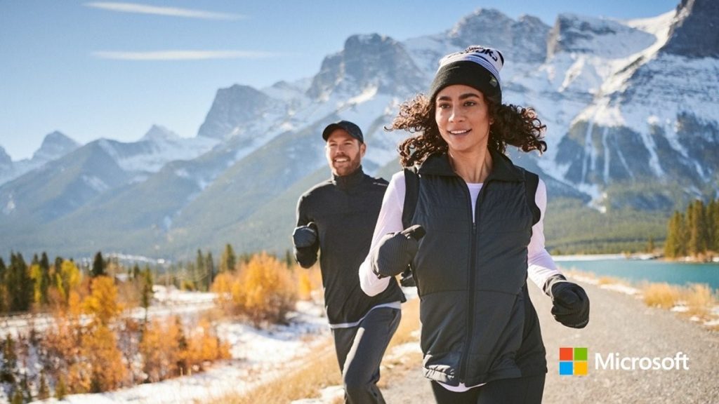 Photo d’une femme et d’un homme courant sur un sentier devant une chaîne de montagnes enneigées.