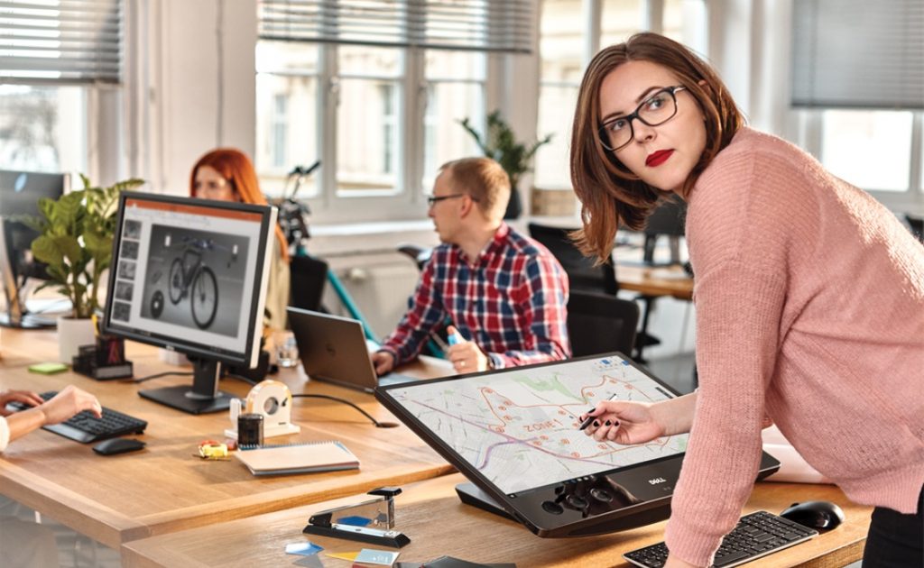 Photo d’un groupe d’employés travaillant ensemble à l’aide de plusieurs ordinateurs dans un studio à aire ouverte.