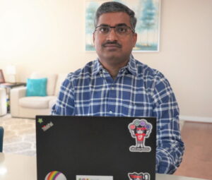 Lathish Chaparala sits with his laptop in front of him and looks at the camera.