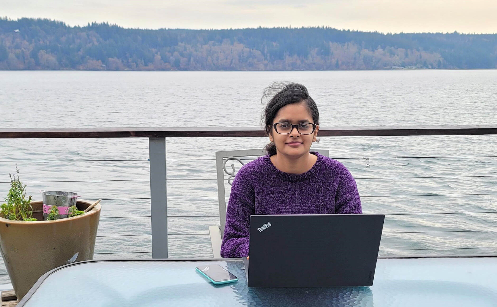 Gaurav, on a back porch overlooking a lake, works from a laptop.
