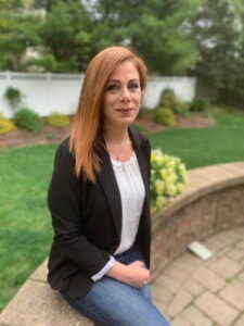 Farnaz Hafezi sits atop a waist-high brick wall in a backyard.