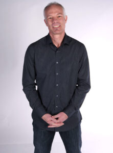 Shaffer stands with his hands clasped in front of him in a corporate photo.