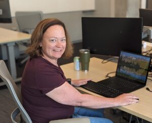 Beth Garrison smiles at a desk with a laptop computer.