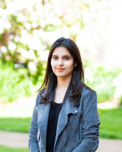 Enjeti faces the camera standing outside in a natural area.