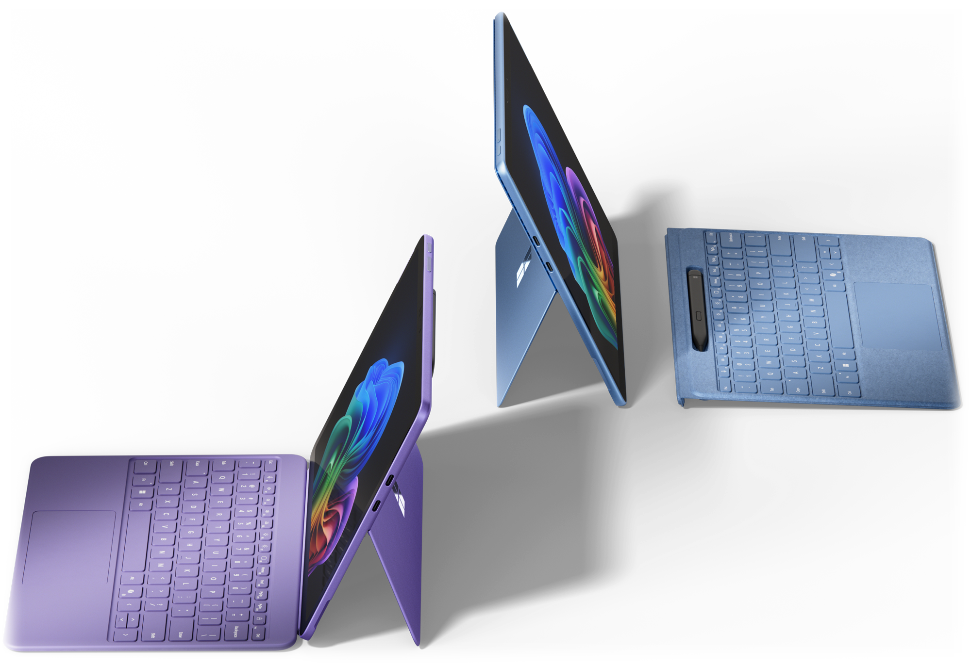 左側に紫色のキーボード、右側に青色のキーボードを接続した2台のMicrosoft Surfaceデバイス。