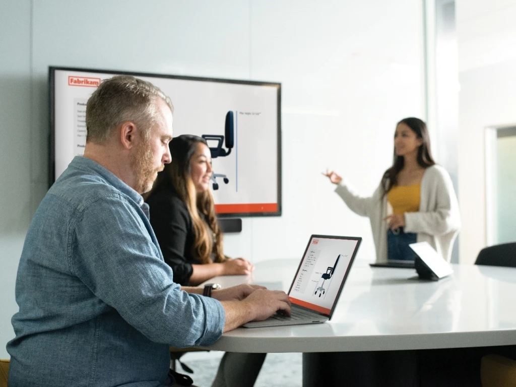 会議室の大型ディスプレイをPCと連動させて製品を検討する男女