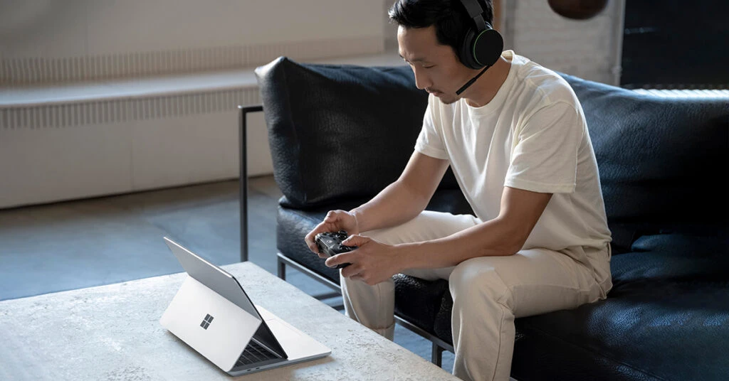 ラップトップ PC 画面をコントローラーで操作するヘッドセットを付けた男性