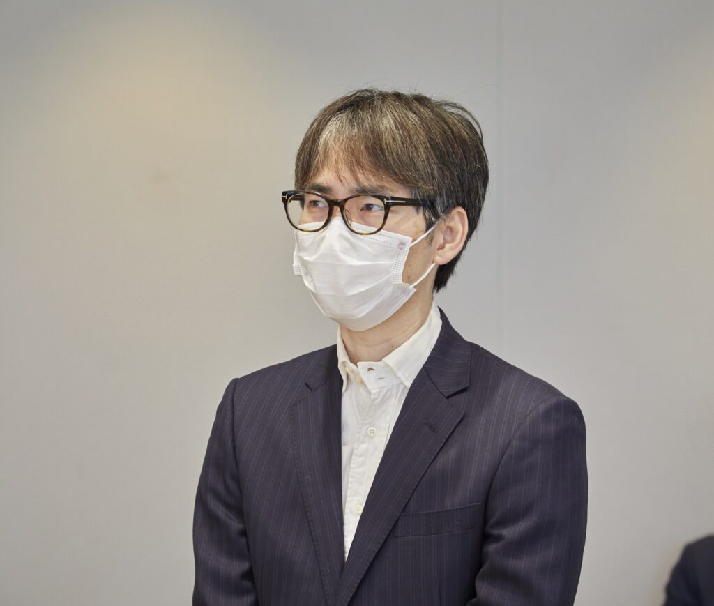 会議室で全体に向けて説明をする男性