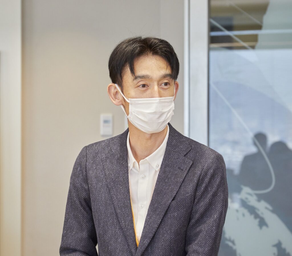 会議室で全体に向けて説明をする男性