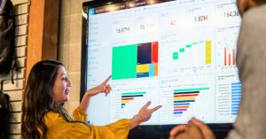 大きなモニターに映されたデータを指差しながらディスカッションする様子