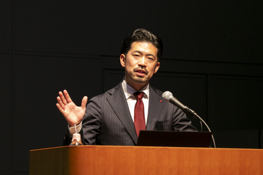 A man in a suit and tie standing at a podium with a microphone