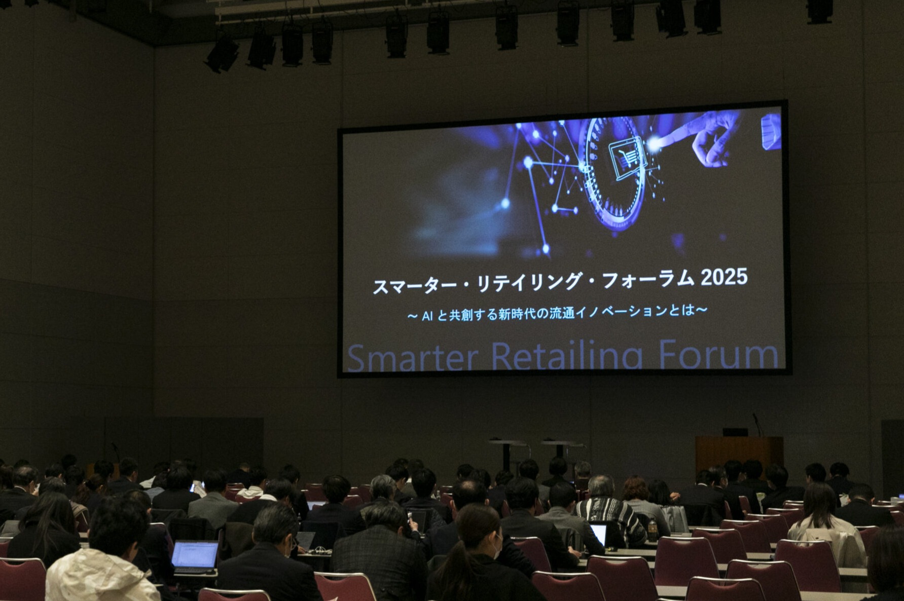 A group of people sitting in a room with a large screen