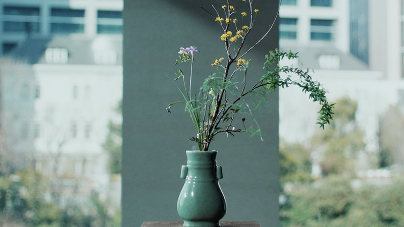 テーブルの上の花瓶に生けられた花と、背景に見える建物
