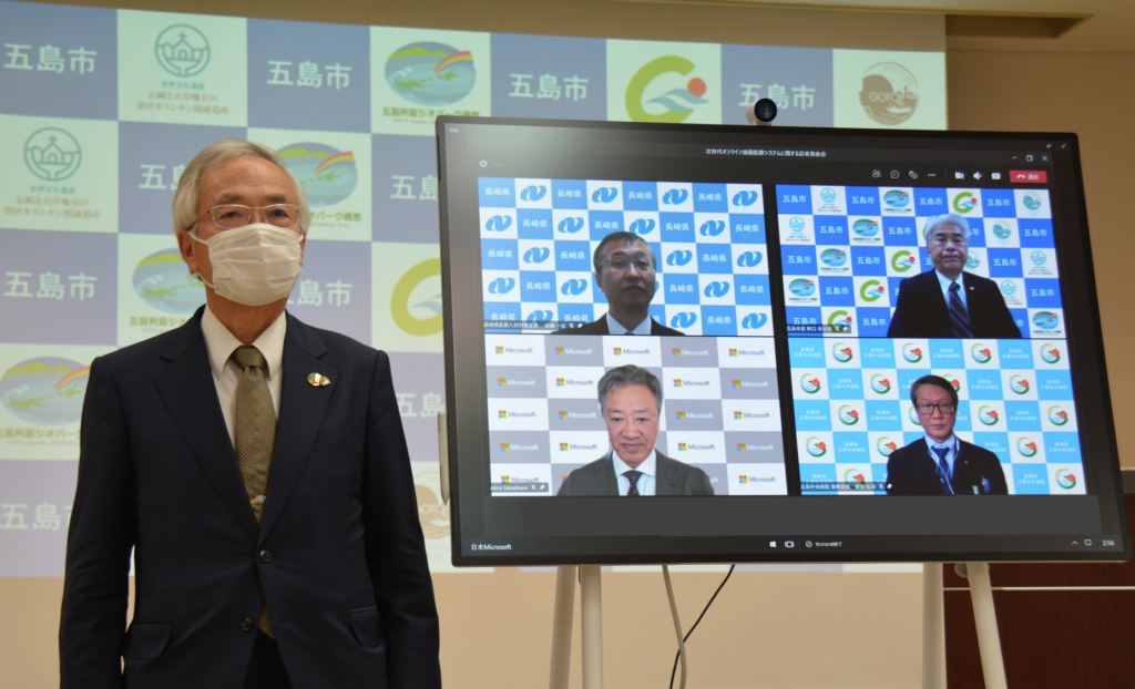 テレビ画面で 4 人の男性と会議をしている人