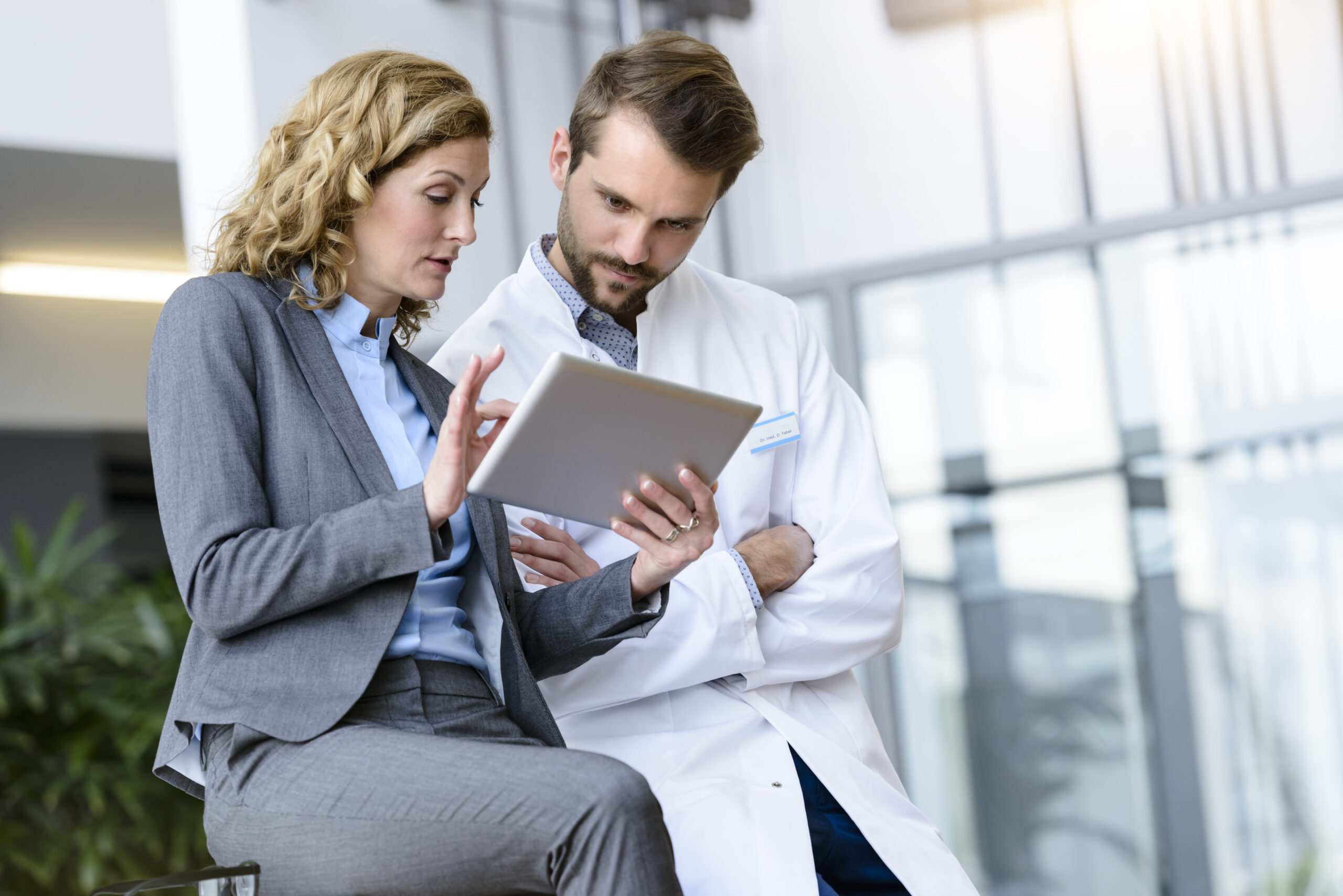 Doctor and professional reviewing information on a tablet. Health care; Microsoft Cloud for Healthcare; health solutions; clinical applications; doctor; provider; office; clinical documentation. Usage approved only for Cloud for Healthcare applications