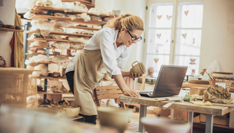 Uma mulher em um atelier olhando para um notebook em uma mesa
