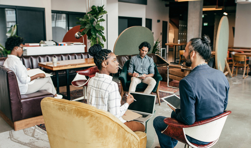 4 homens e uma mulher sentados em um escritório utilizando tablets