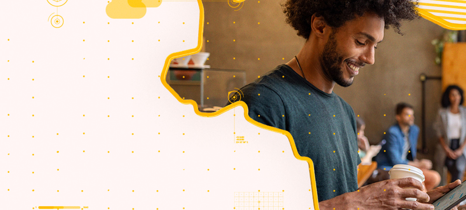 Um homem com um copo de café na mão mexendo em um tablet com pessoas desfocadas ao fundo