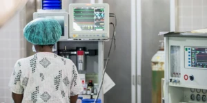 Imagem de profissional médico em frente a um aparelho conectado com fios