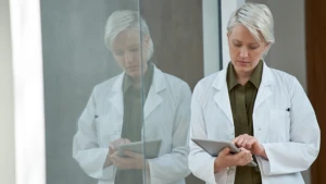 Mulher, de idade média, pessoal de saúde sustentando um tablet em suas mãos. Se encontre junto a um vídeo que sirva como espelho e reflexo