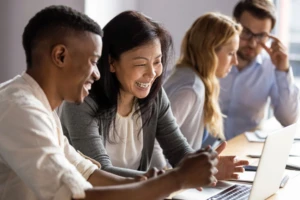 "Empresária madura e feliz discutindo um projeto no laptop com uma jovem colega.