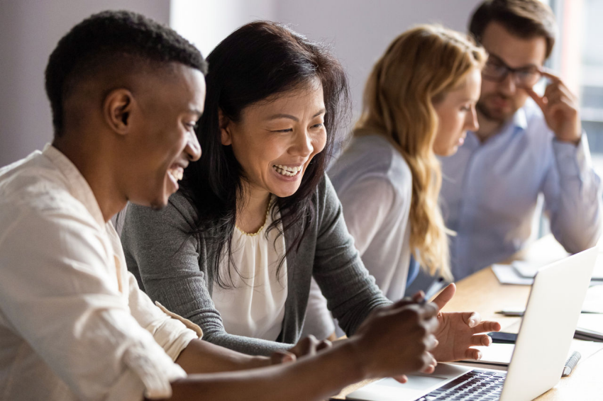 "Empresária madura e feliz discutindo um projeto no laptop com uma jovem colega.
