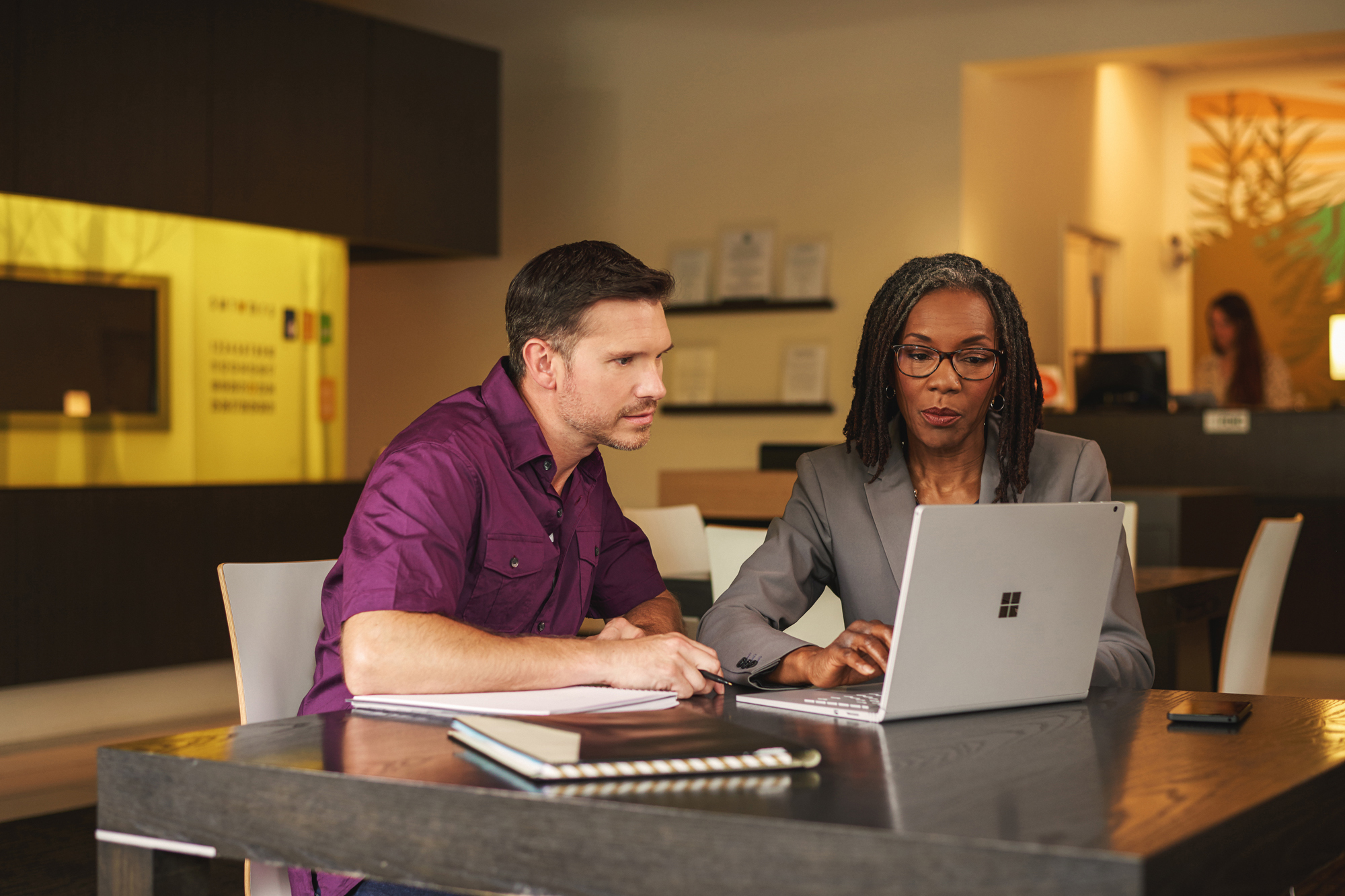 Financial analyst helping a customer on a Surface Book in a bank