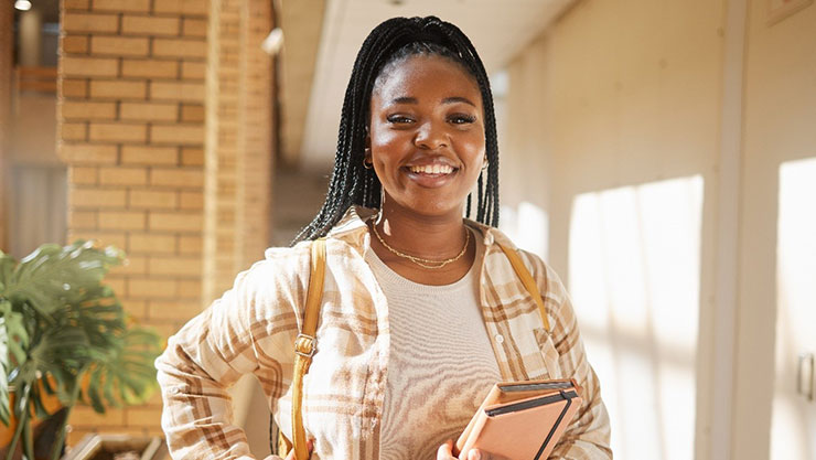 Woman smiling while carrying 2 books in the left hand